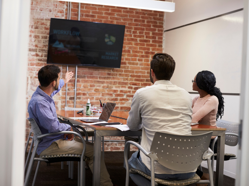 Three employees in a small meeting room having a discussion